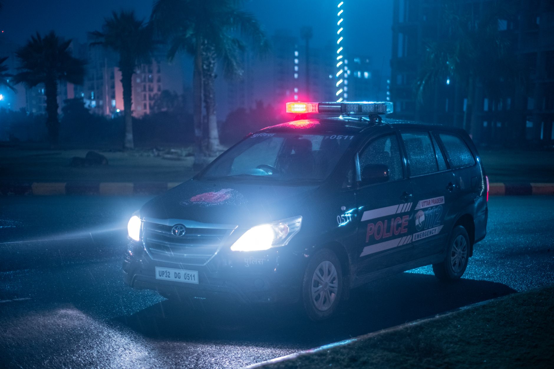 Carro escuro com luzes de viatura policial refletindo à noite